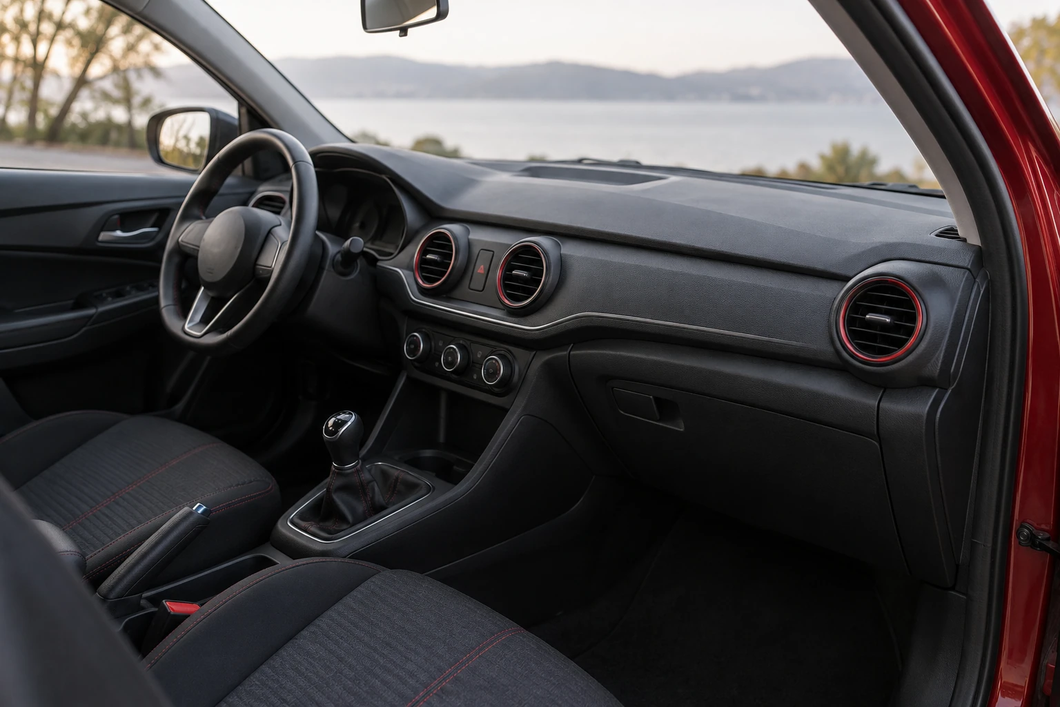 Intérieur de voiture compact avec volant, tableau de bord et aérateurs ronds rougeâtres